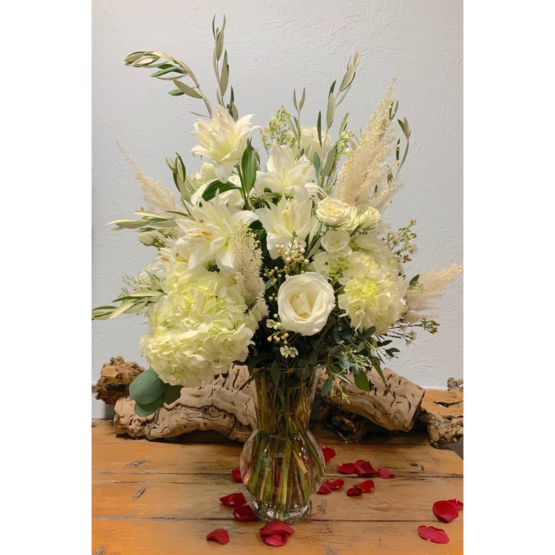 Silent Night- All White Florals with Olive Branches and wax flower in a tall glass vase
